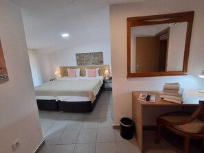 A hotel room with a bed, bedside table, chair, and a mirror. - Largo da Fonte (Serta)