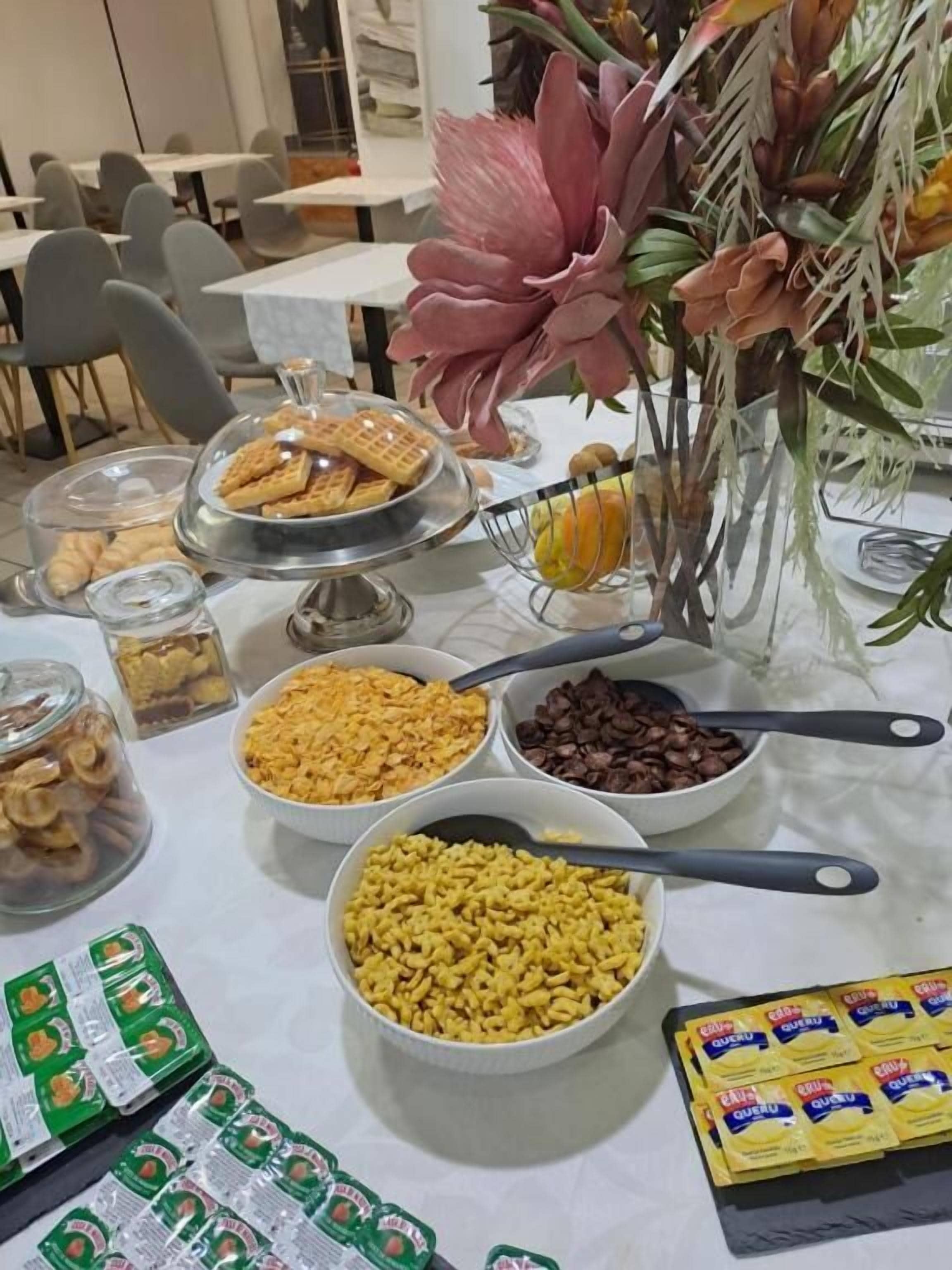 A buffet table with various food items and condiments, including waffles, cereal, nuts, and chocolate chips.