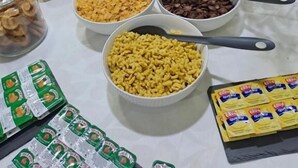 Une table de buffet proposant divers aliments et accompagnements, notamment des gaufres, des céréales, des noix et des pépites de chocolat.