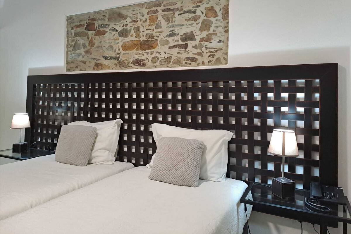 Ein Hotelzimmer mit einem Bett, zwei Nachttischen und einem an der Wand hängenden Kunstwerk.