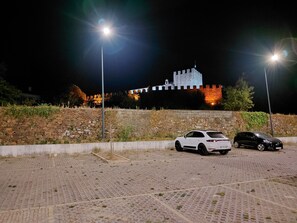 A parking area with two cars and a castle-like structure in the background. - Largo da Fonte (Serta)