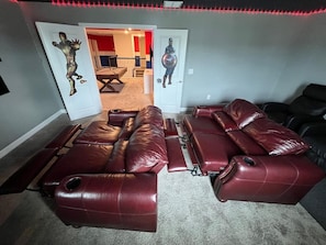 A home theater setup with a red leather couch and a reclining chair.