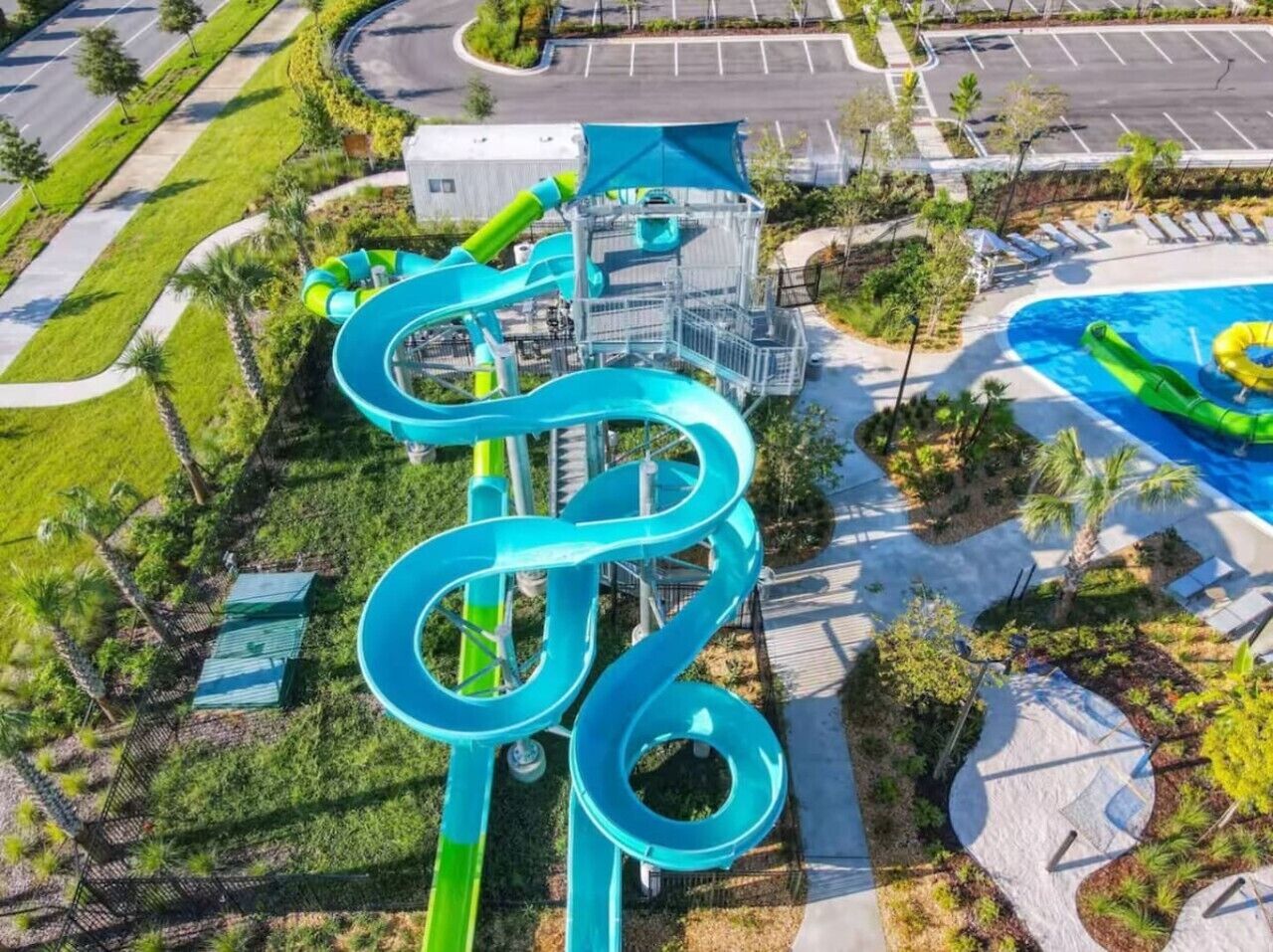 Un parc aquàtic amb un tobogan espiral gran, una piscina i un pàrquing.
