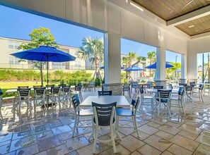 Un espace extérieur aménagé en terrasse, avec des tables et des chaises, des parasols et une vue sur le paysage environnant.
