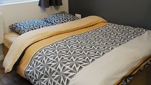 A bedroom with a bed, a window with curtains, and two wall-mounted shelves with plants. - Renovated studio 5 minutes from the city center (Rouen)