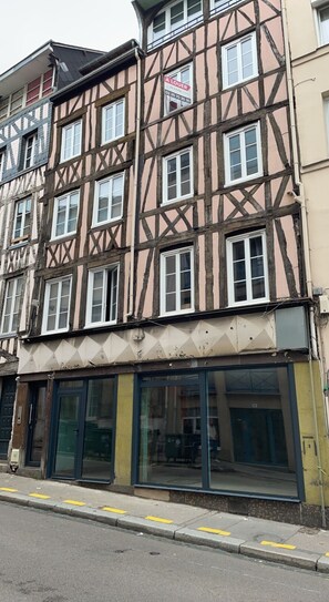 Un edificio tradicional con entramado de madera, varias ventanas y una tienda en la planta baja con amplios puertas de vidrio.