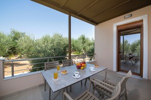 A balcony with a table set for breakfast, including fruits, juice, and pastries. - Villa Amelia, modern and tasteful house in Cretan nature (Rethymno)