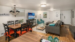 A modern living room with a wooden dining table, a TV, and a sofa.