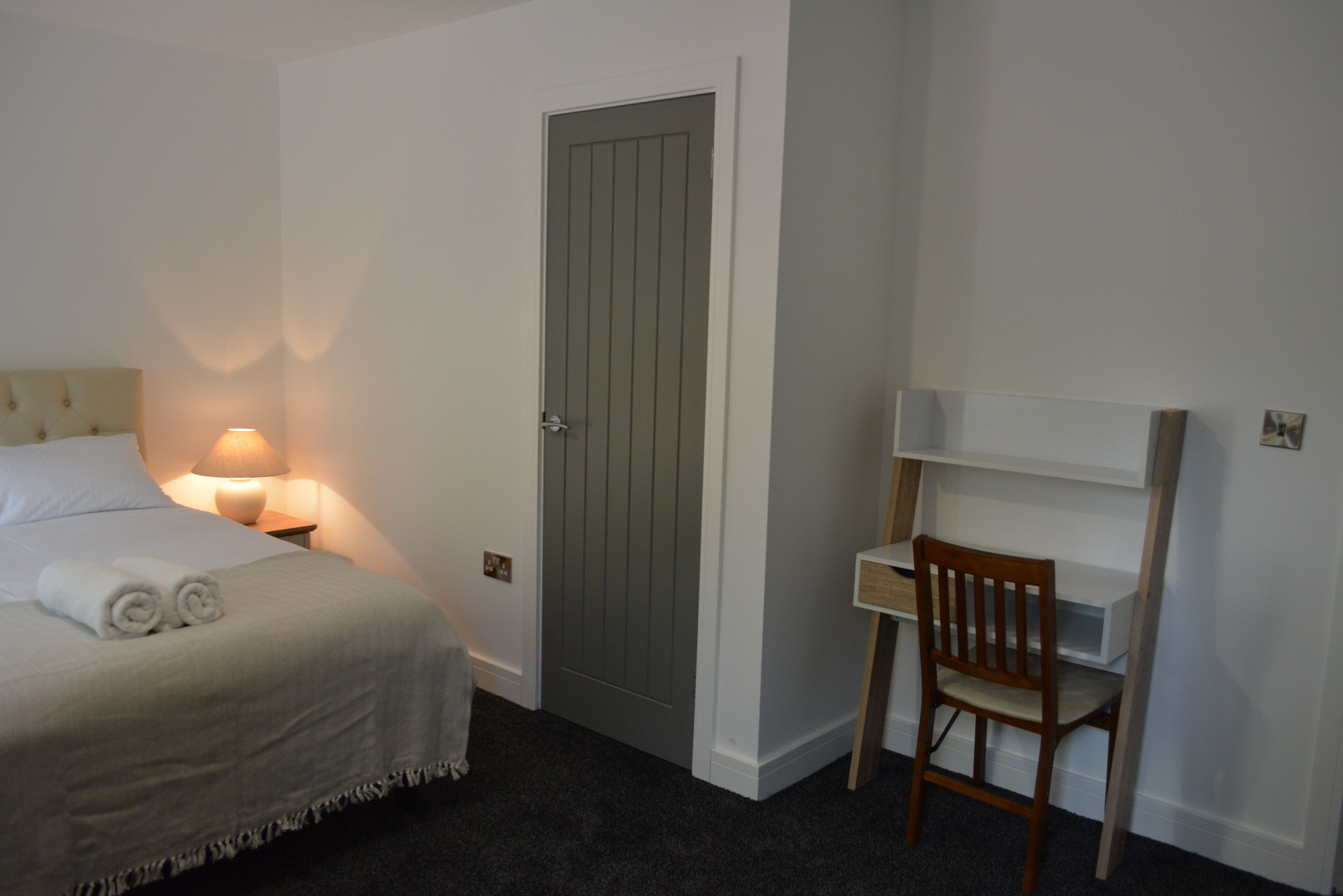 A bedroom with a bed, a desk, and a chair.