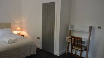 A bedroom with a bed, a desk, and a chair.