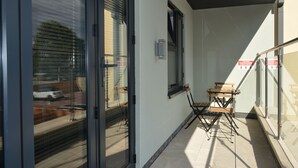 Un balcón con puerta de vidrio, una mesita y una silla.