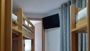 A room with bunk beds, a television, and a curtain. - Hostel Sertã (Serta)