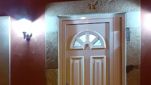 A door with a decorative arch and a small window above it, set in a wall with a textured finish. - Hostel Sertã (Serta)