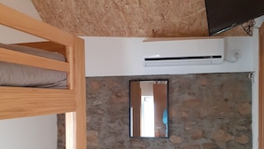 A room with a bunk bed, a desk with a chair, a mirror, and an air conditioning unit. - Hostel Sertã (Serta)