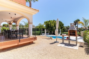 Ein überdachter Außenbereich mit Pool, Grill und Sitzgelegenheit.