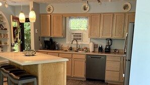 A modern kitchen with wooden cabinets, a central island, pendant lighting, and a refrigerator. - gaze at Seneca Rocks from living room sofa (Seneca Rocks)