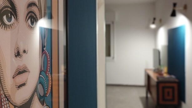 A hallway with a poster on the left, a desk with a lamp, and a door at the end. - Apartment with kitchen-living room, 3 bedrooms, 2 bathrooms, laundry. (Bologna)