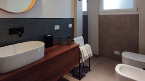 A modern bathroom with a large oval sink, a wooden vanity, a round mirror, and a toilet. - Apartment with kitchen-living room, 3 bedrooms, 2 bathrooms, laundry. (Bologna)