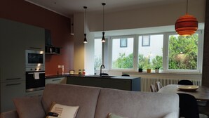 A modern kitchen with a built-in oven, a dining area with a table and chairs, and a sofa with decorative pillows. - Apartment with kitchen-living room, 3 bedrooms, 2 bathrooms, laundry. (Bologna)