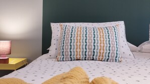 A bed with patterned pillows and a yellow blanket, a bedside lamp, and a yellow box on a nightstand. - Apartment with kitchen-living room, 3 bedrooms, 2 bathrooms, laundry. (Bologna)