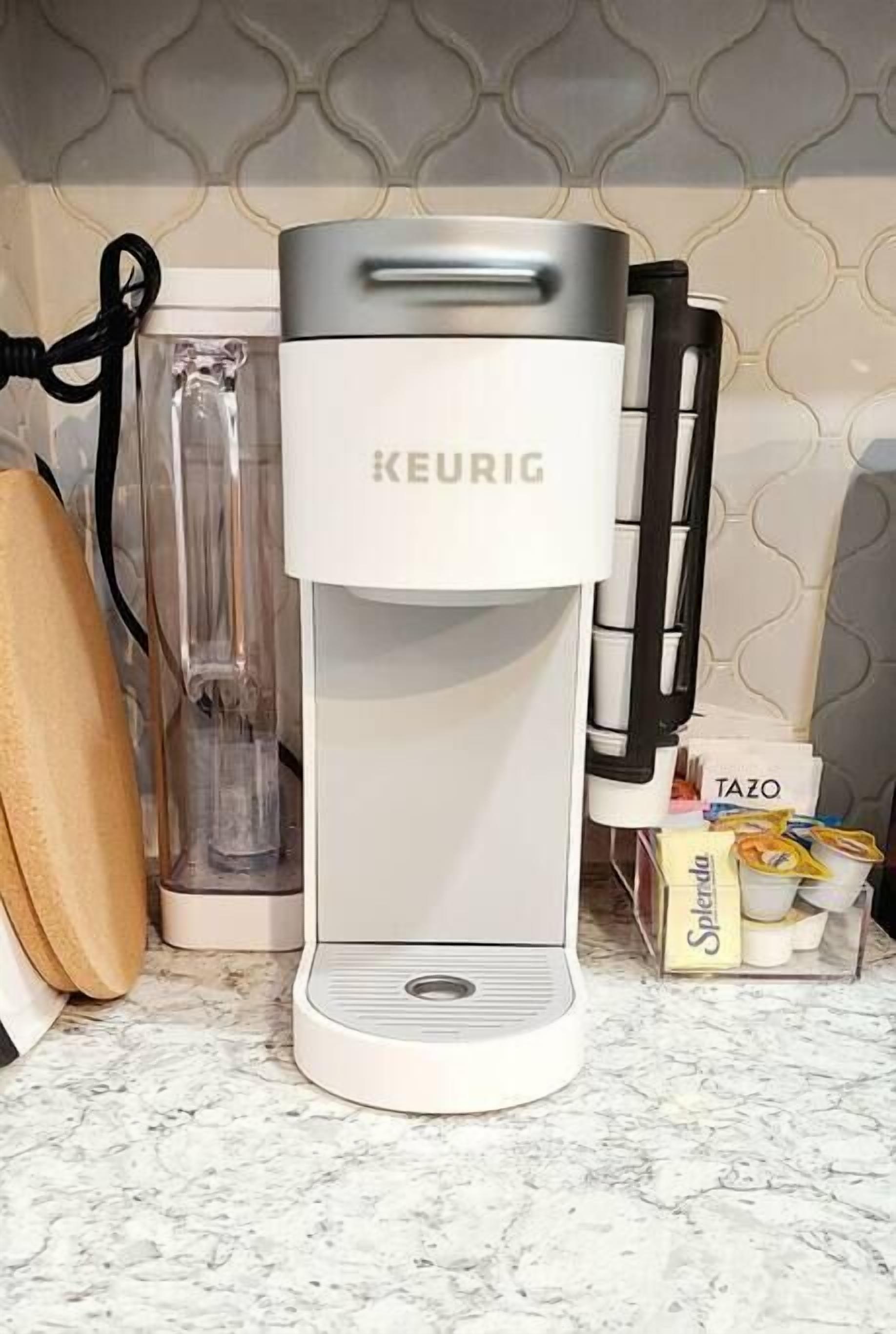 Una cafetera KEURIG sobre una encimera de cocina con salpicadero de mármol.