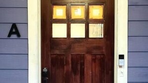 A wooden front door with a stained glass window above it, a mailbox, and a 'Welcome' mat at the entrance. - West End Jewel on Sunset (Winston-Salem)