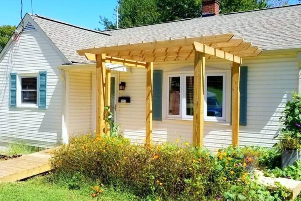 A house with a covered porch, a small garden with flowers, and a wooden deck.