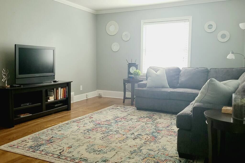 A living room with a television, sofa, and a patterned rug.