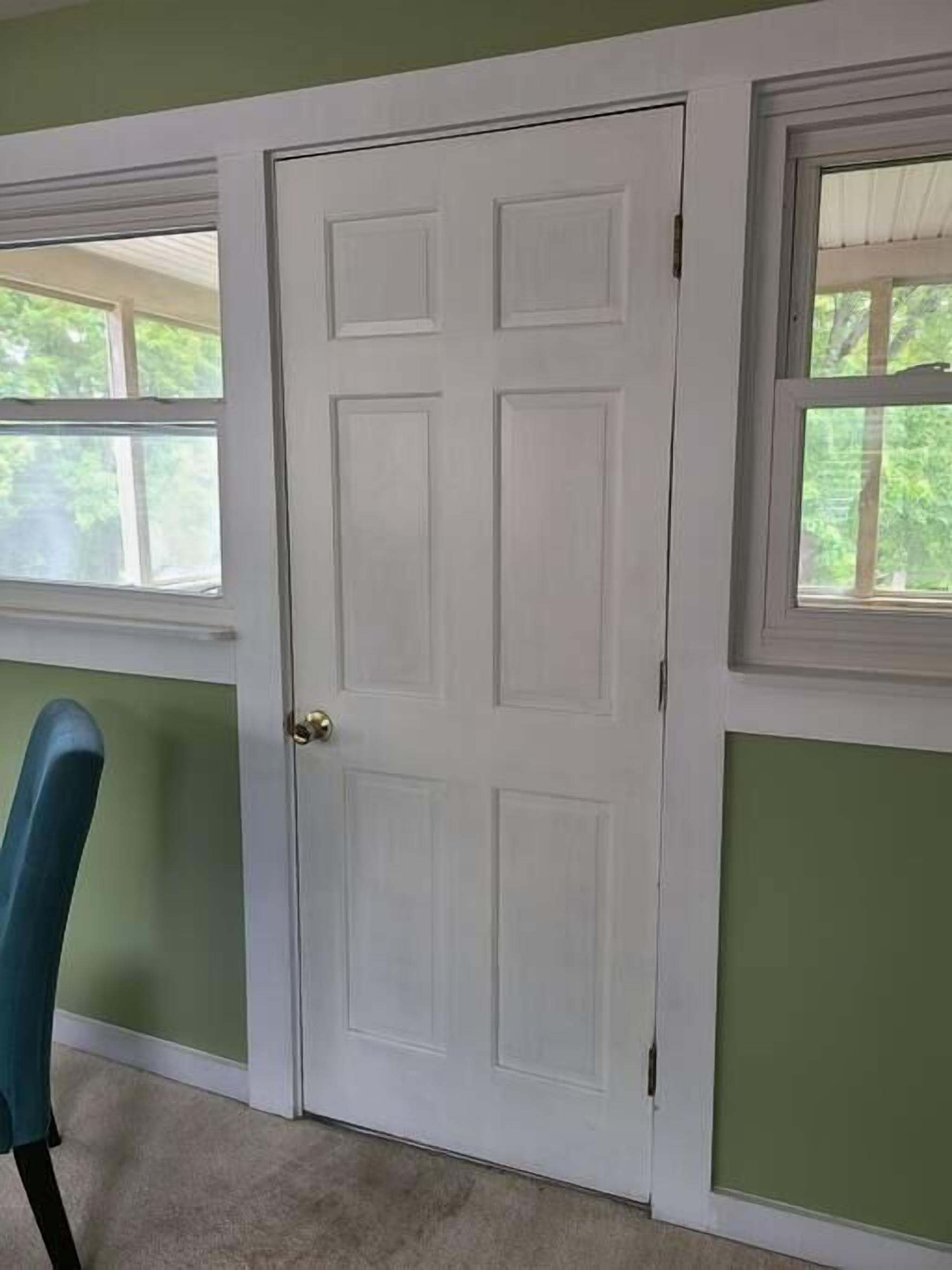 A room with a white door, a window with a white frame, and a green wall.