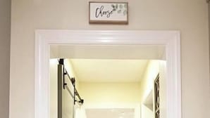 Un couloir avec un sol carrelé, une porte à gauche et une pancarte au-dessus de la porte sur laquelle on peut lire « Choisissez ».
