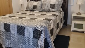 A bedroom with a large bed, two bedside tables, and a door.