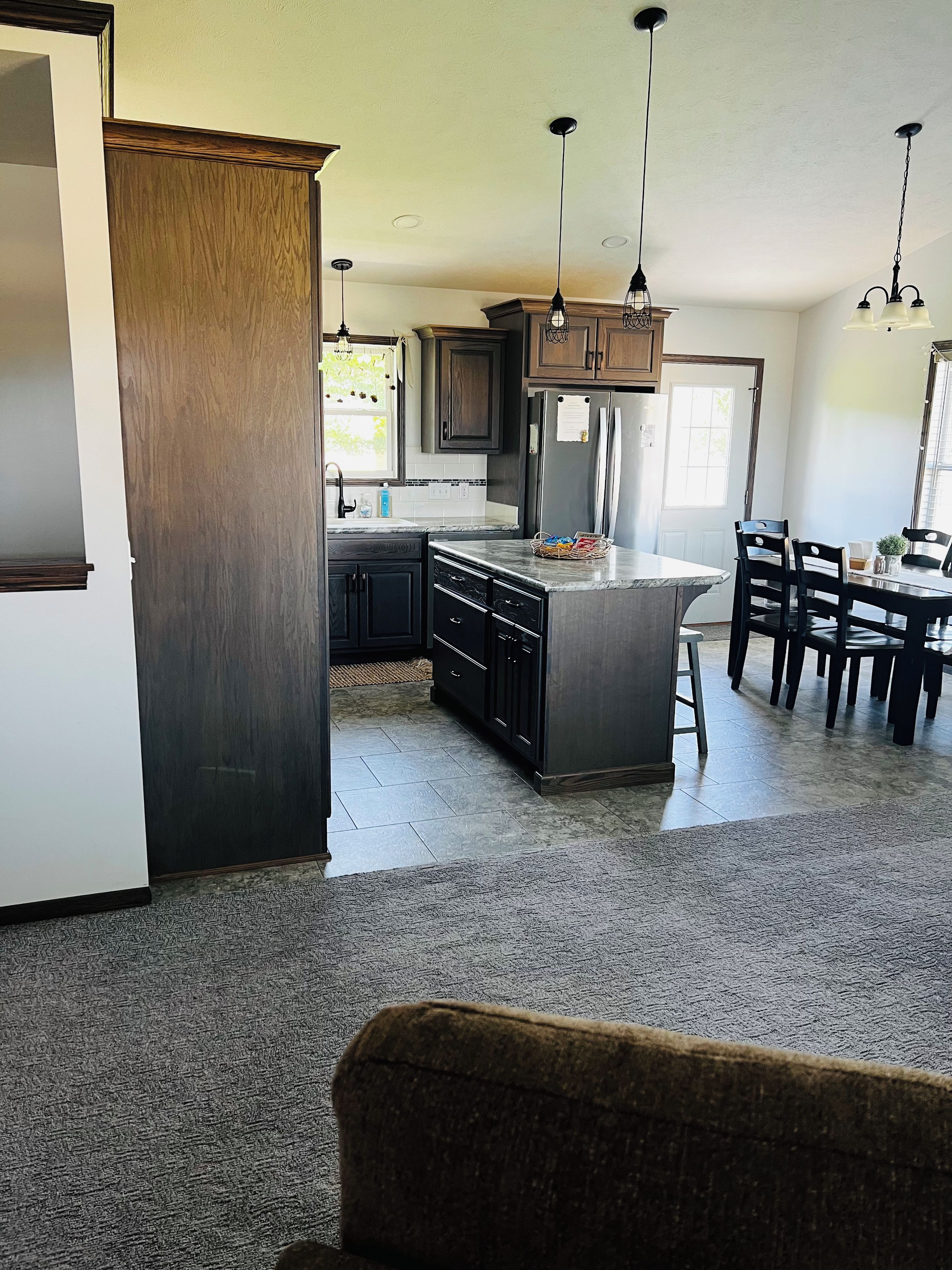 A modern kitchen with dark wood cabinets, a central island, and pendant lighting.