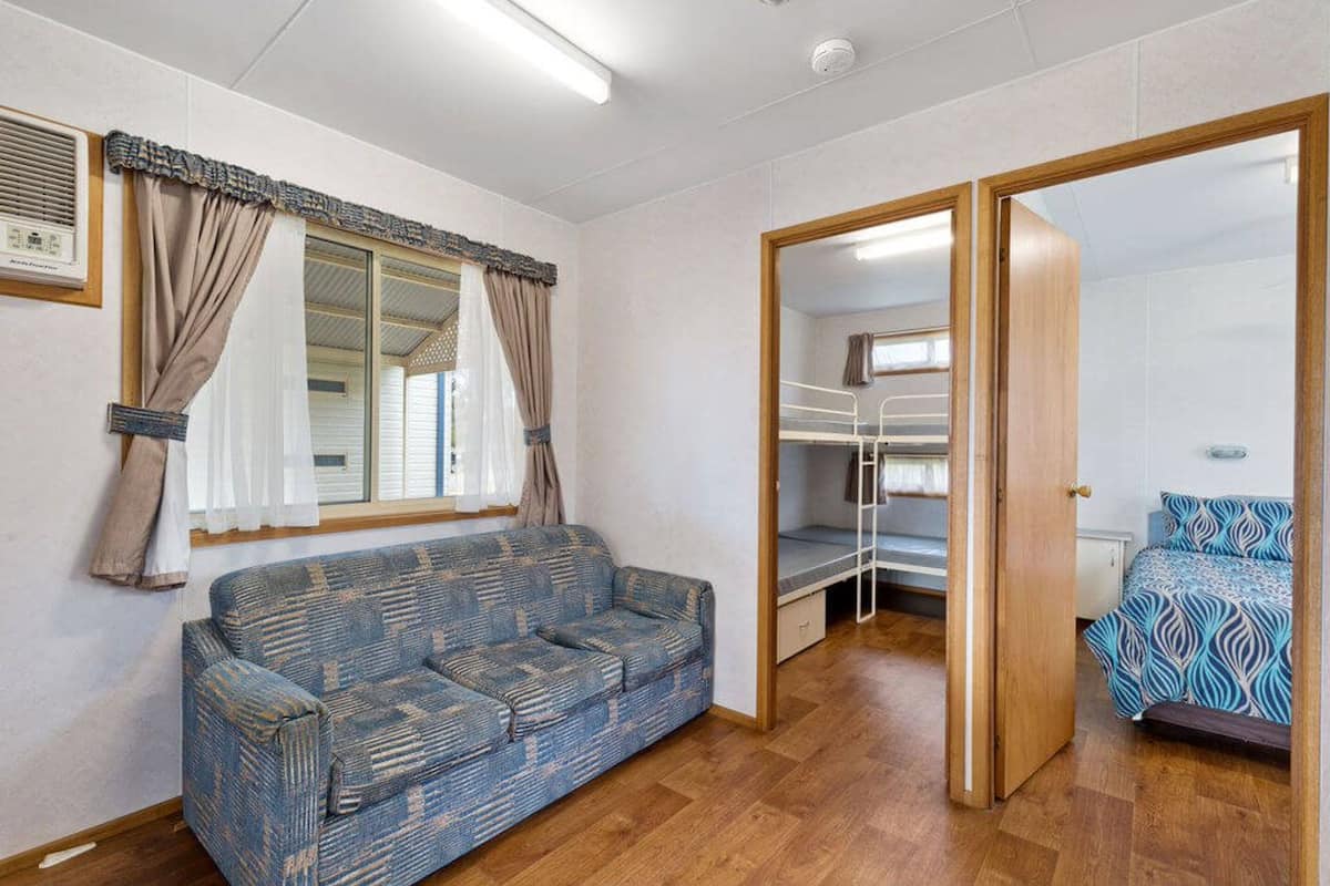 A room with a sofa, a bed, a wardrobe, and a window with curtains.