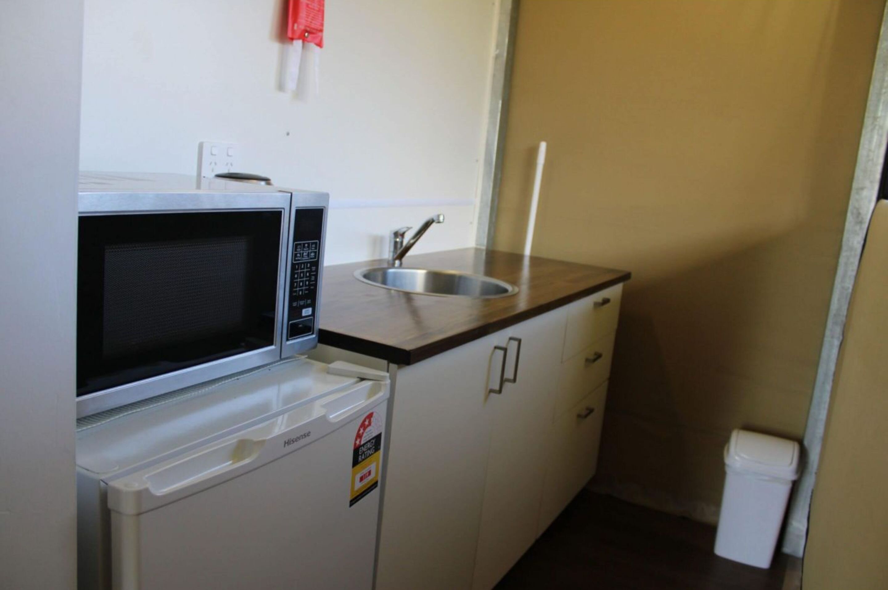 A compact kitchenette with a microwave, a small sink, and a compact refrigerator.