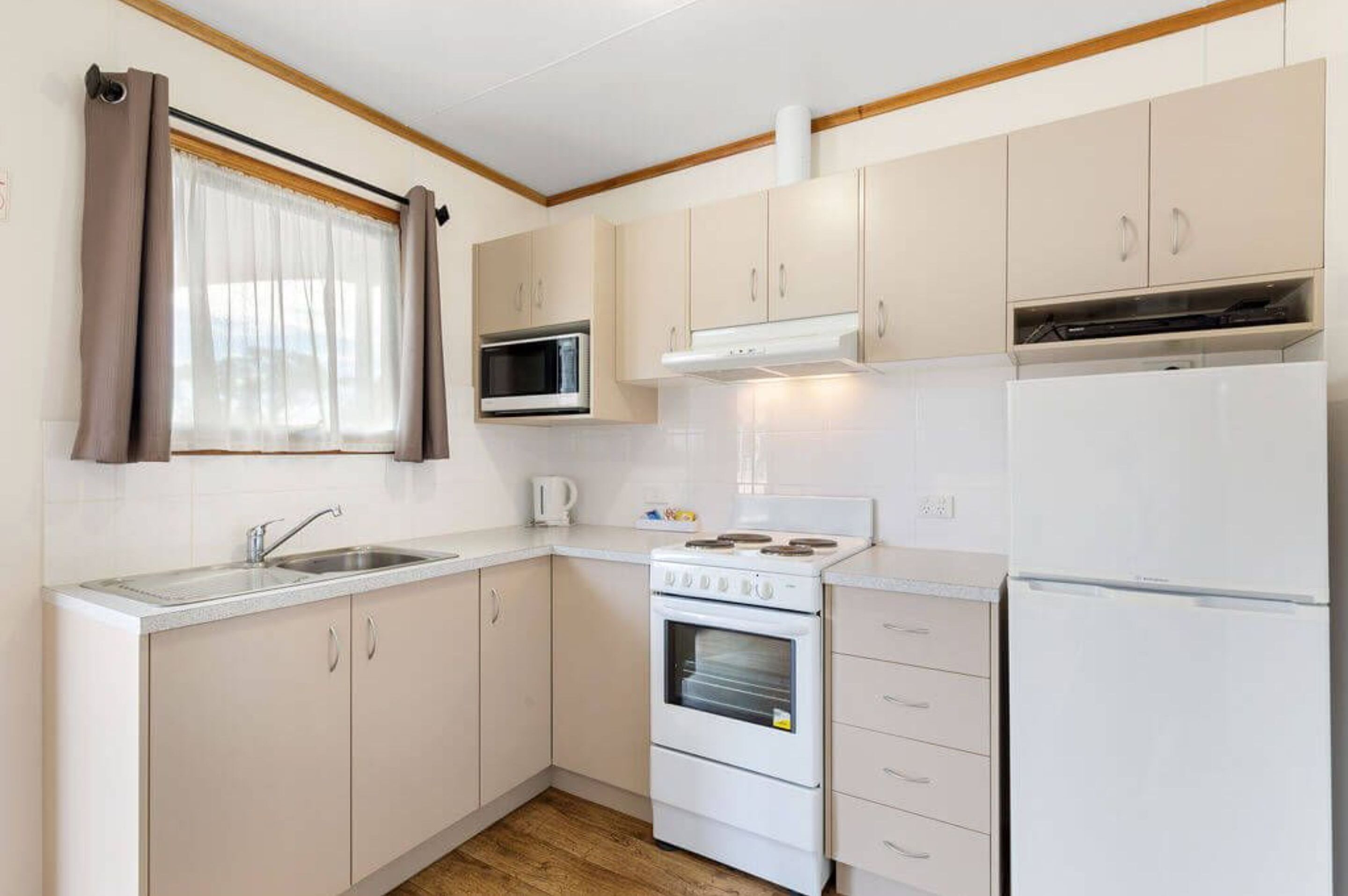 A compact kitchen with a sink, stove, microwave, and refrigerator.