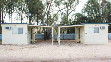 Two small, single-story mobile homes with a covered outdoor area, surrounded by trees.