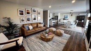 Ein modernes Wohnzimmer mit einer braunen Ledersofa, einem Couchtisch und einem Essbereich mit weißen Stühlen.