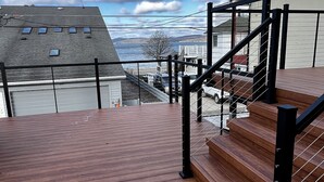 Ein Holzdeck mit einer Metalltreppe, die zu einer erhöhten Ebene führt.