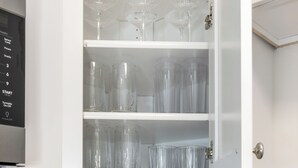 A kitchen with a cabinet containing wine glasses and a cutting board with knives. - TigerTown Retreat - Comfort Minutes from Campus (Central)