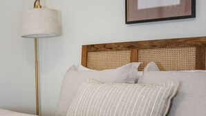A neatly made bed with a striped pillow, a plain lamp, and a framed picture on the wall. - TigerTown Retreat - Comfort Minutes from Campus (Central)