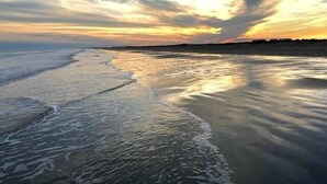 A beach with a calm sea and a sunset. - "Above the Waves" - BEACH FRONT (Galveston)