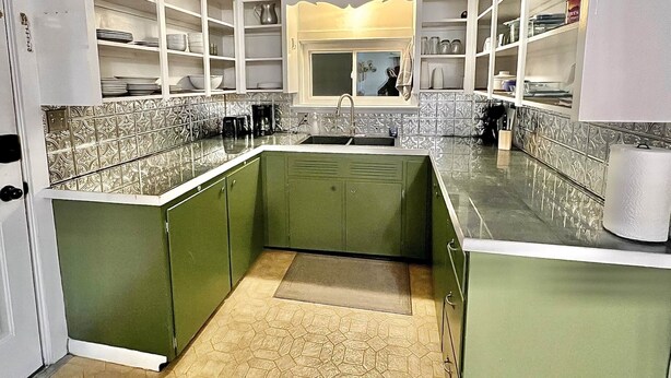 A kitchen with green cabinets, white shelves, and a tiled backsplash. - Munising Lakeview Getaway (Munising)