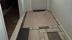 A hallway with a white door, a window, and a rug leading to a room. - Munising Lakeview Getaway (Munising)
