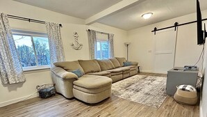 A living room with a sectional sofa, a rug, a lamp, and a small cabinet. - Munising Lakeview Getaway (Munising)