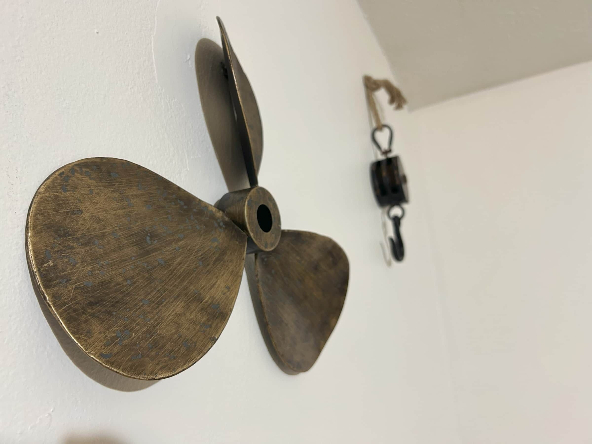 Un ventilateur de plafond au design rustique, un interrupteur mural et un porte-clés.