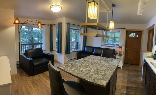 A modern kitchen with a granite countertop, black leather seating, and pendant lighting.