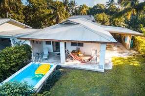 Uma casa com piscina, rede e área de varanda.