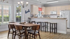 A modern kitchen with a central island, bar stools, and a dining table with chairs. - Cozy Condo//Pool/Workspace/Dogs Stay for Free! (Myrtle Beach)