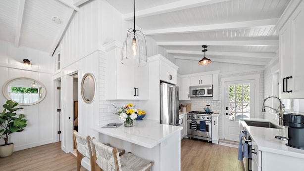 A kitchen with white cabinetry, a central island, and a hanging light fixture.
