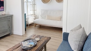 A room with a wooden coffee table, a blue sofa, a white couch, and two woven wall decorations.